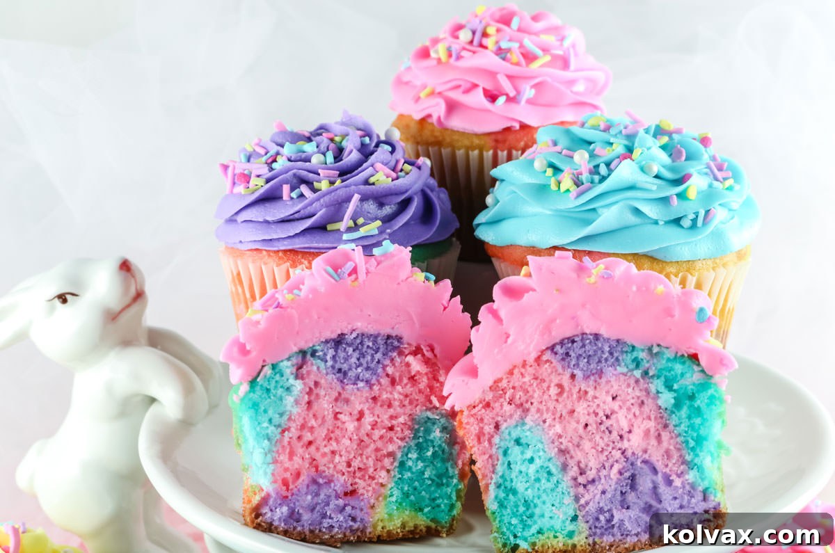 Four Celebration Marble Cupcakes sitting on a white Easter Cake Stand with a Bunny, showcasing pastel swirls of pink, purple, yellow, and blue frosting.