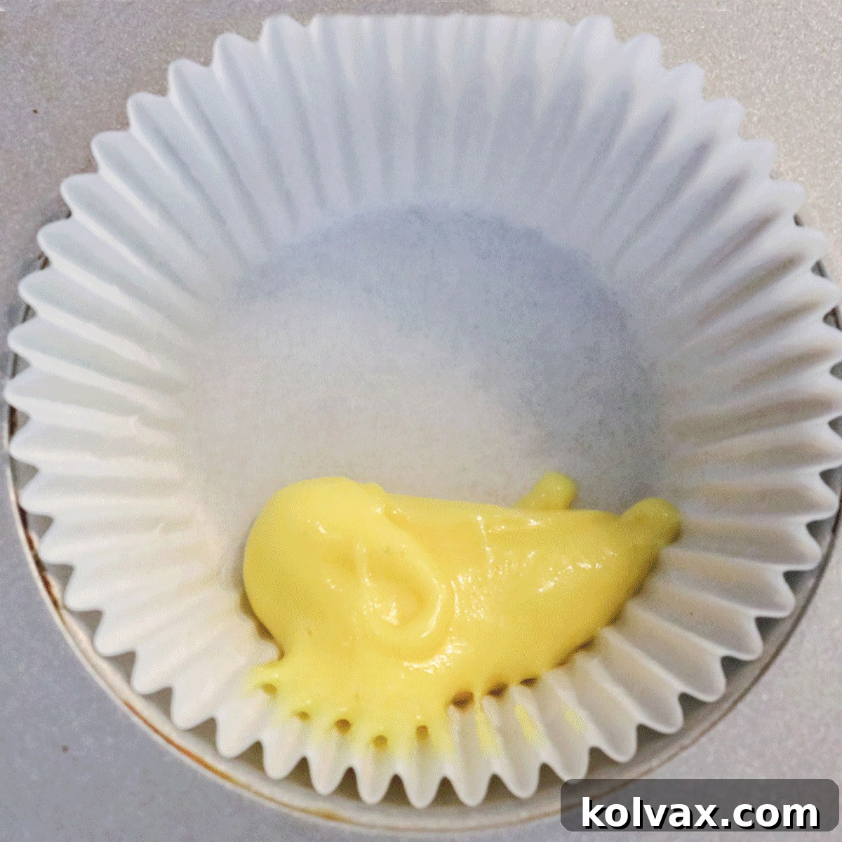 Animated GIF demonstrating the process of spooning small, alternating drops of colored cupcake batter into a cupcake liner to achieve a beautiful marble pattern.