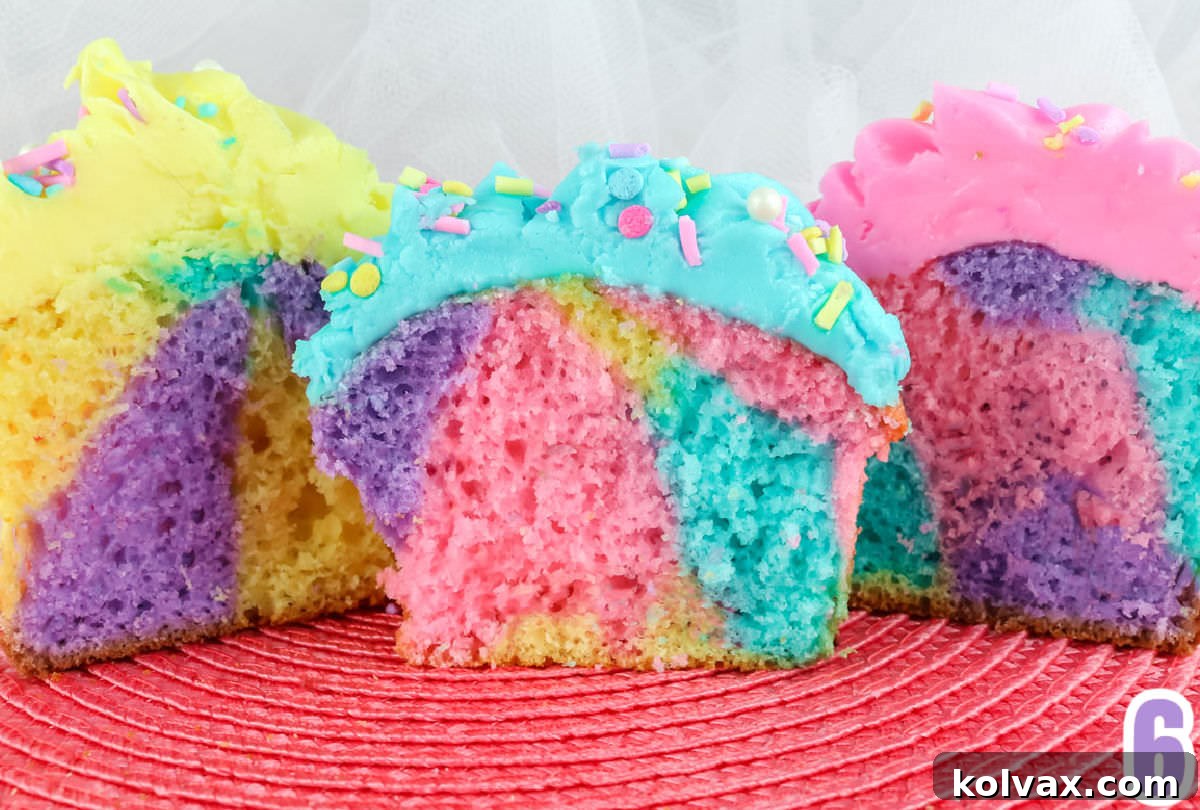 The cut insides of three Celebration Marble Cupcakes, each displaying a unique and vibrant pastel marble pattern.