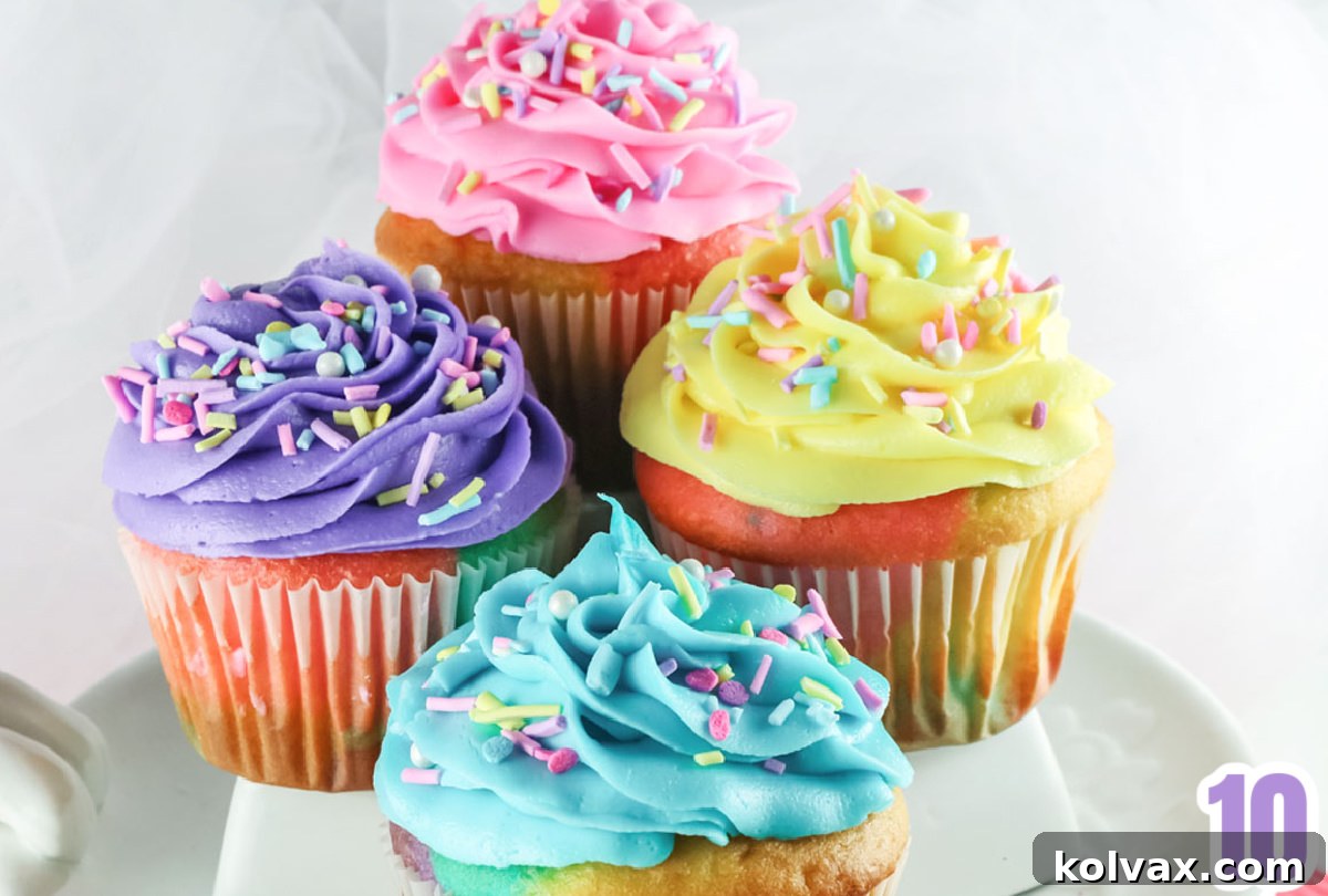 A closeup showcasing the delicate yellow, pink, purple, and blue frosting swirls of Buttercream Frosting on top of Celebration Marble Cupcakes, adorned with matching sprinkles.