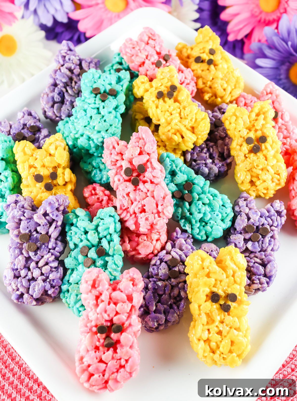 A beautiful white serving platter overflowing with an assortment of colorful Rice Krispie Easter Bunny Peeps, placed on a soft pink placemat, creating a festive Easter display.