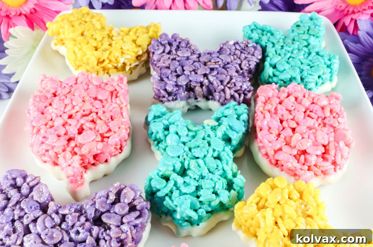 Closeup of a white platter filled with colorful Rice Krispie Treats that have been dipped in White Chocolate.