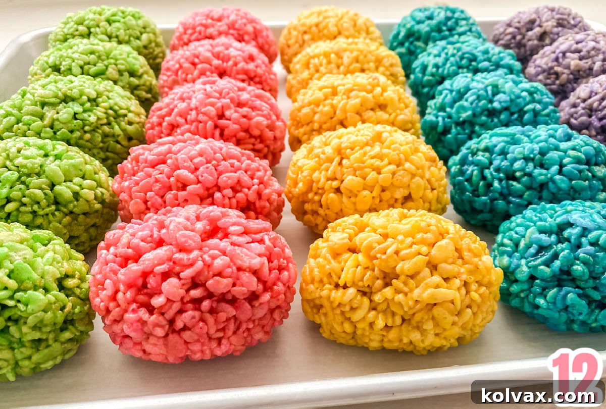 A vibrant cookie sheet filled with an assortment of multi-colored Rice Krispie Treat Easter Eggs, ready to be placed into the decorative basket.