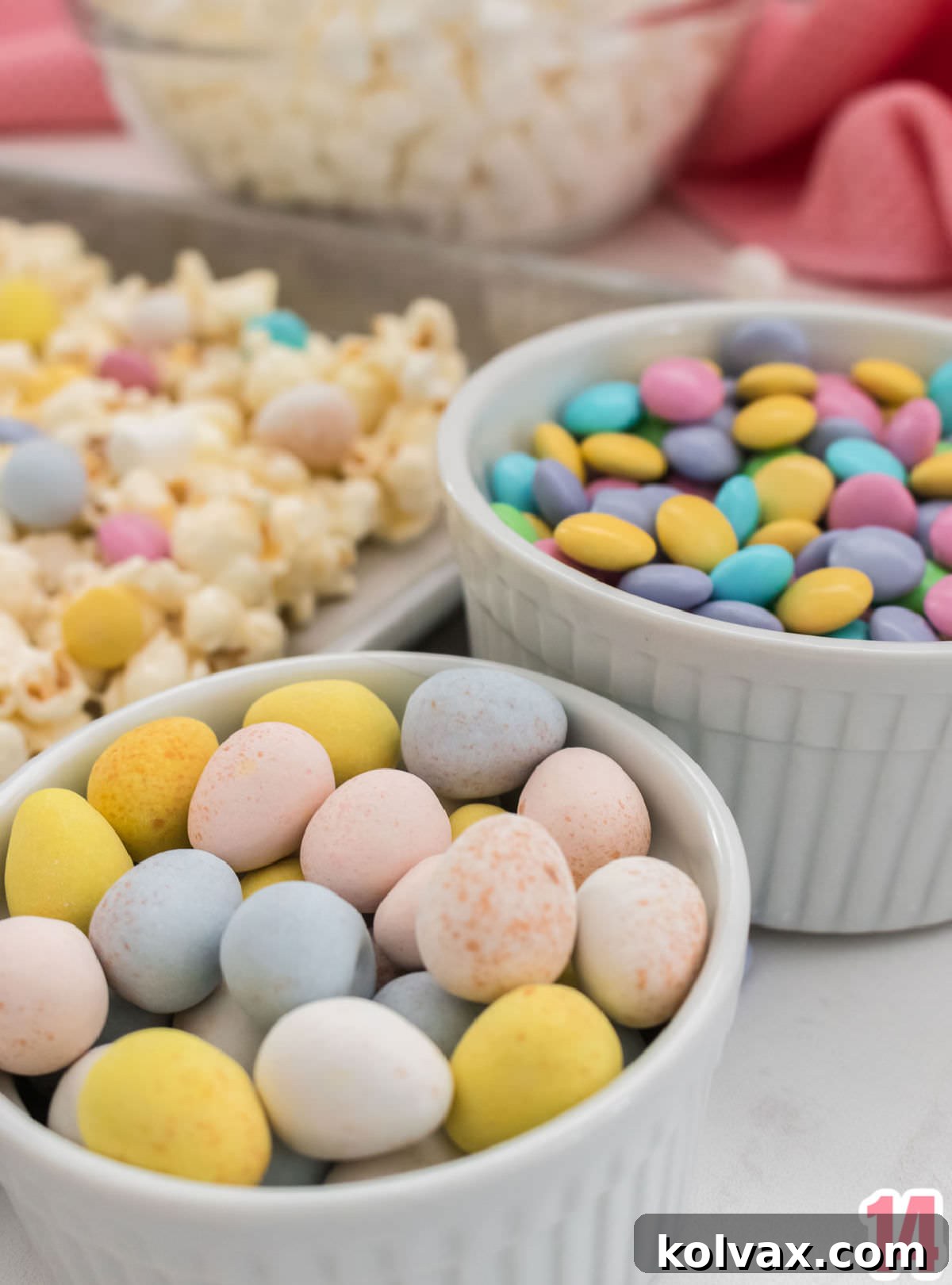 Close up on Hard Candy Easter Eggs and Easter Mix M&M's sitting next to a cookie sheet filled with Easter Candy Popcorn, showcasing the vibrant colors.